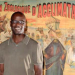 Lilian Thuram devant une affiche de l'exposition montrant des "sauvages" exposés au Jardin d'Acclimatation de Paris (Zoo)