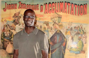 Lilian Thuram devant une affiche de l'exposition montrant des