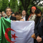 Pierre Audin portant le drapeau algérien, Pierre Mansat au centre, à l’arrière-plan.