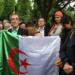 Pierre Audin portant le drapeau algérien, Pierre Mansat au centre, à l’arrière-plan lors de l'inauguration du cénotaphe.